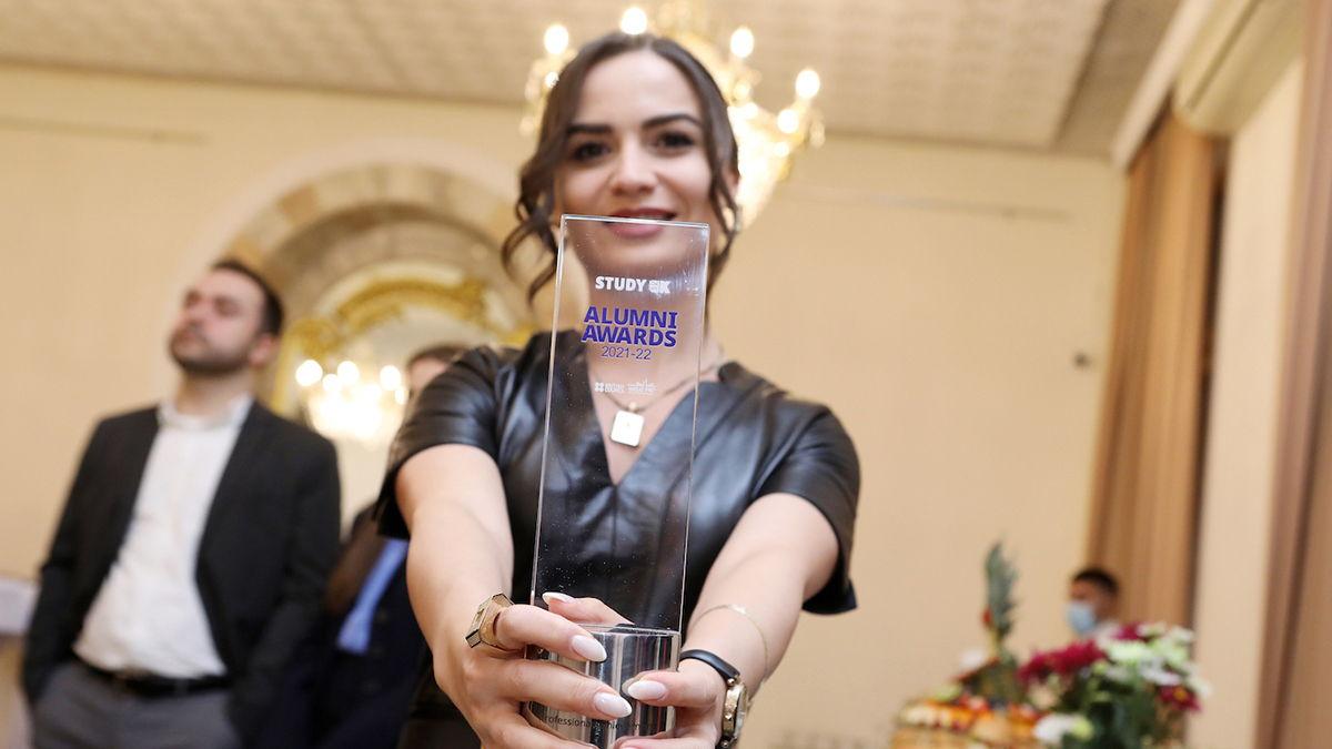 An Alumni Award winner holding up her trophy